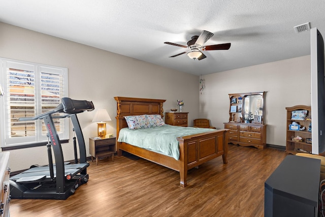 bedroom with visible vents, ceiling fan, a textured ceiling, wood finished floors, and baseboards