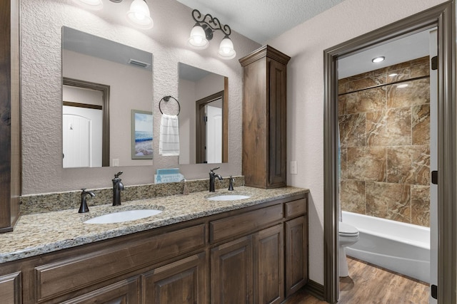 full bathroom with toilet, wood finished floors, a sink, and visible vents