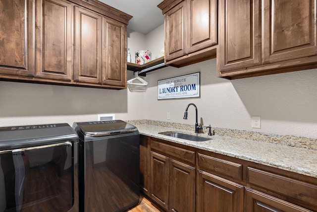 laundry area featuring washing machine and clothes dryer, a sink, and cabinet space