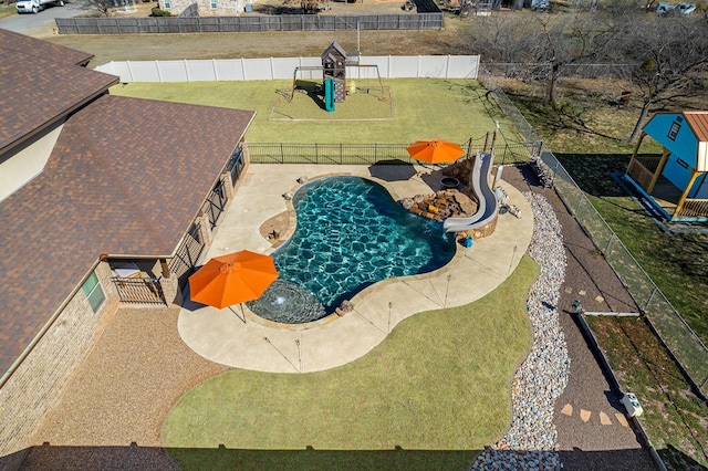 view of swimming pool featuring a fenced backyard, a playground, a water slide, and a yard