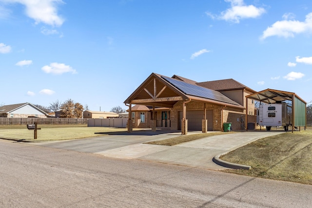 view of front of home with brick siding, concrete driveway, an attached garage, roof mounted solar panels, and fence