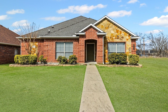 view of front of property with a shingled roof, a front yard, stone siding, and brick siding