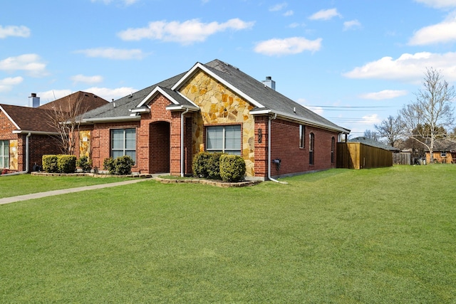 single story home featuring stone siding, brick siding, a front yard, and fence