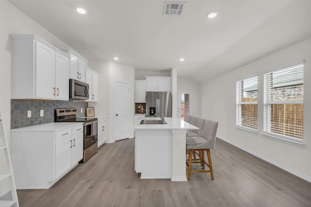 kitchen with stainless steel appliances, visible vents, backsplash, white cabinets, and a sink