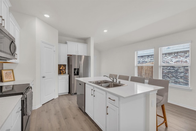 kitchen featuring appliances with stainless steel finishes, light wood-type flooring, a sink, and a kitchen breakfast bar