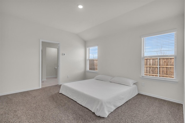 carpeted bedroom with lofted ceiling and baseboards