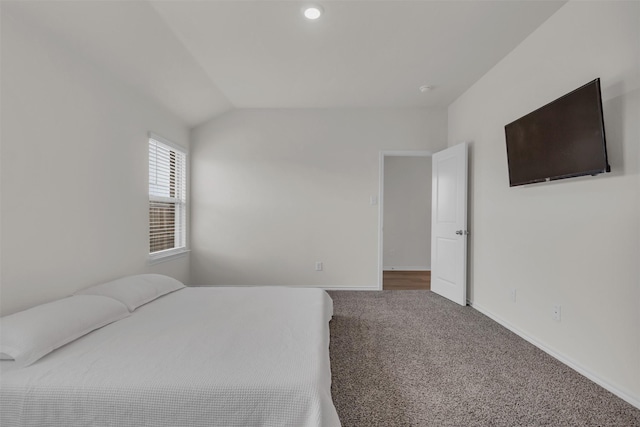 carpeted bedroom with vaulted ceiling and baseboards