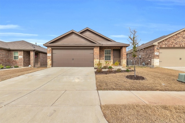 view of front of home featuring driveway, an attached garage, central AC unit, and brick siding