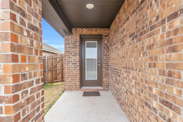 property entrance with brick siding and fence