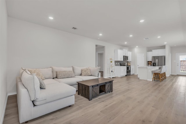 living area with light wood-type flooring, baseboards, visible vents, and recessed lighting