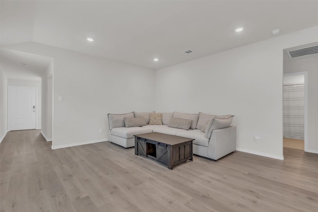 living room with light wood-style flooring, visible vents, and baseboards