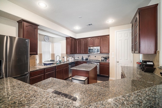 1202 Newcastle St, Roanoke, TX 76262 - kitchen featuring stainless steel appliances, tasteful backsplash, dark stone countertops, recessed lighting, and a sink