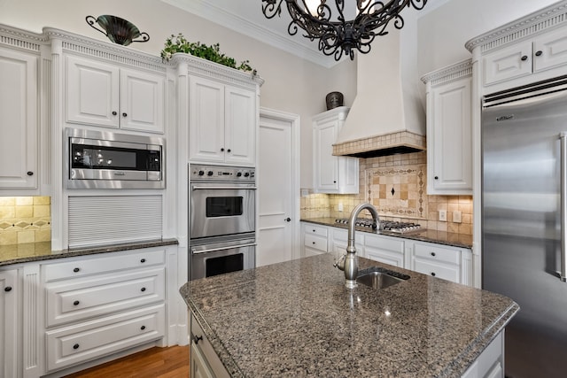 kitchen with built in appliances, a sink, crown molding, premium range hood, and backsplash