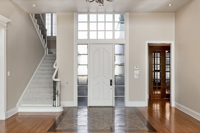 entryway featuring stairs, a chandelier, and wood finished floors