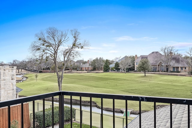 balcony with view of golf course and a water view