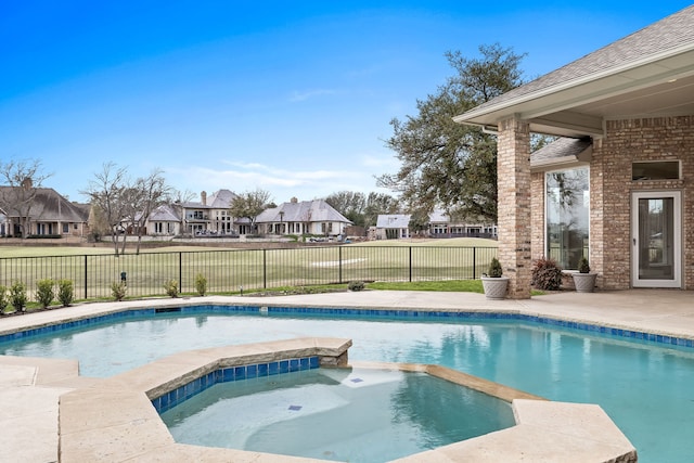 view of pool with a residential view, a pool with connected hot tub, and fence