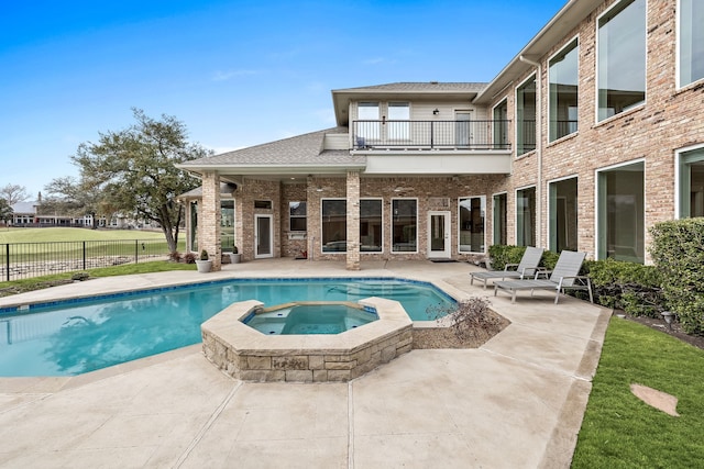 view of pool with a pool with connected hot tub, fence, and a patio