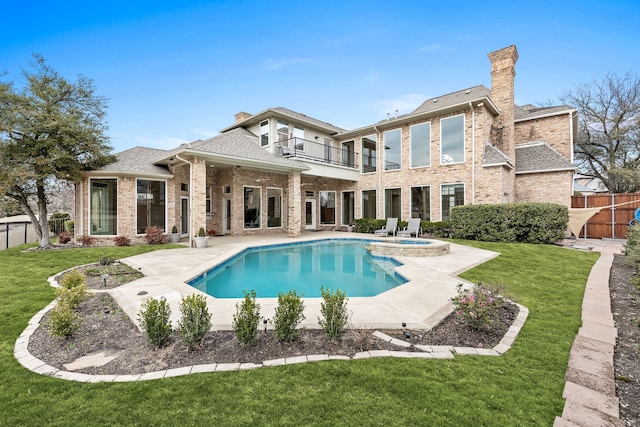 back of house with a patio, a chimney, a lawn, a balcony, and a fenced backyard