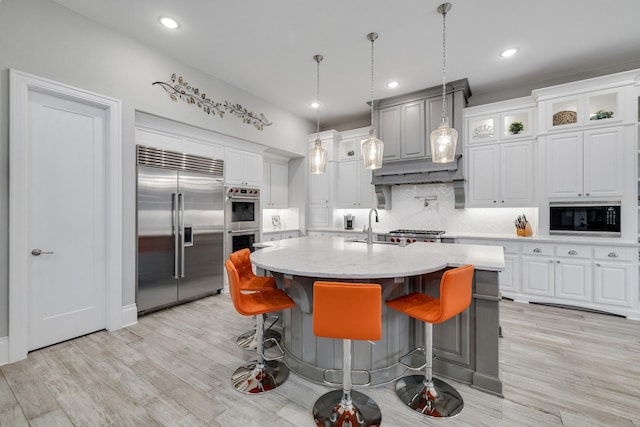 kitchen featuring stainless steel appliances, light wood-type flooring, a sink, and tasteful backsplash