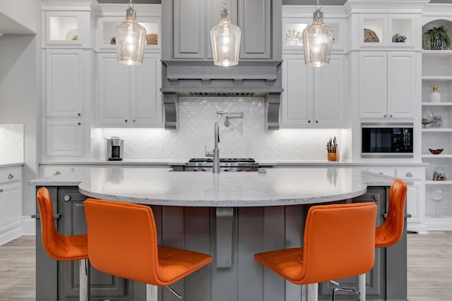 kitchen featuring black microwave, pendant lighting, light wood-type flooring, white cabinetry, and open shelves