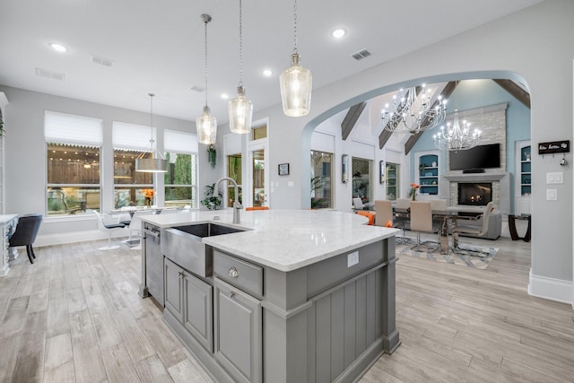 kitchen with a kitchen island with sink, gray cabinets, visible vents, and a sink