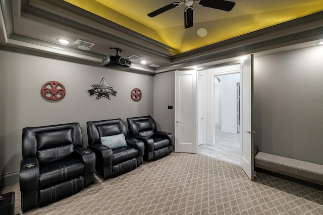 carpeted cinema featuring a ceiling fan, a tray ceiling, visible vents, and vaulted ceiling