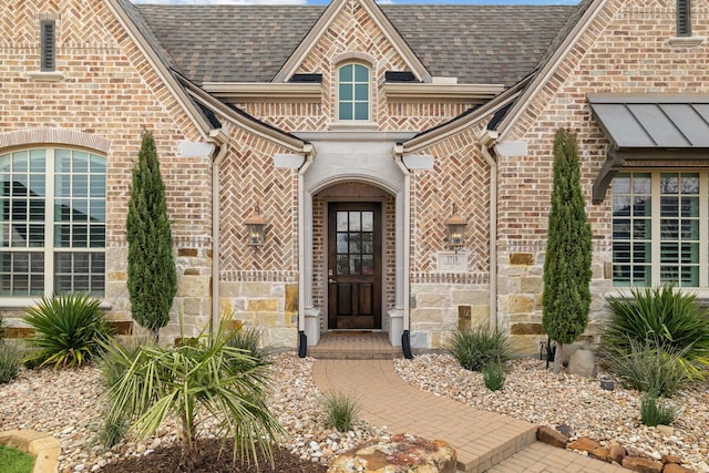 property entrance with stone siding, brick siding, and roof with shingles