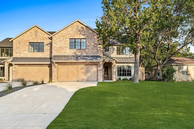 view of front of home featuring brick siding, an attached garage, a front yard, a standing seam roof, and driveway