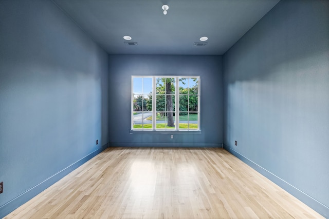 spare room featuring baseboards, visible vents, and wood finished floors