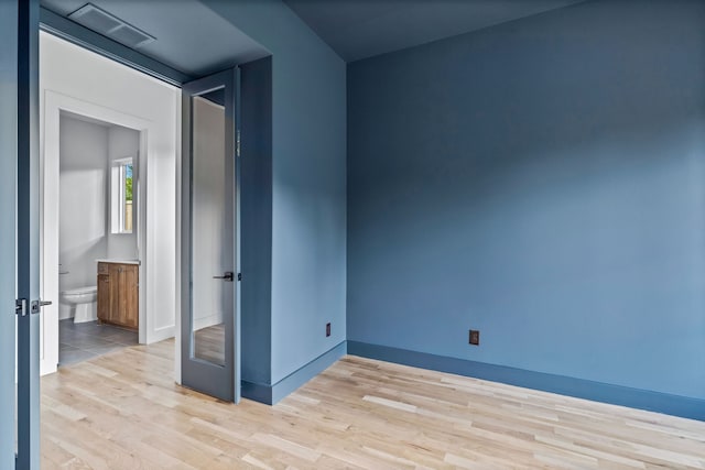 spare room with baseboards, visible vents, and wood finished floors