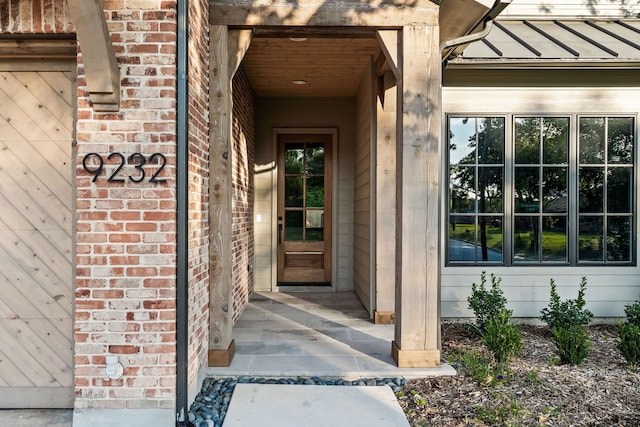 entrance to property with a standing seam roof, metal roof, and brick siding