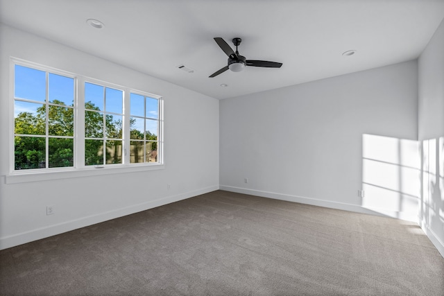 empty room with ceiling fan, carpet flooring, visible vents, and baseboards