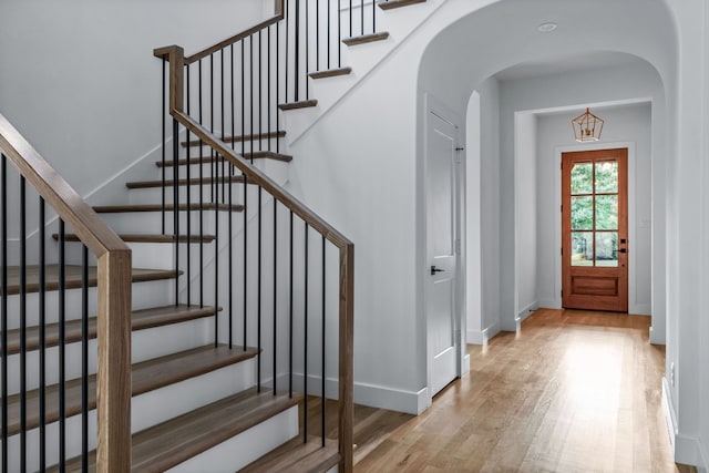 entryway featuring arched walkways, wood finished floors, and baseboards