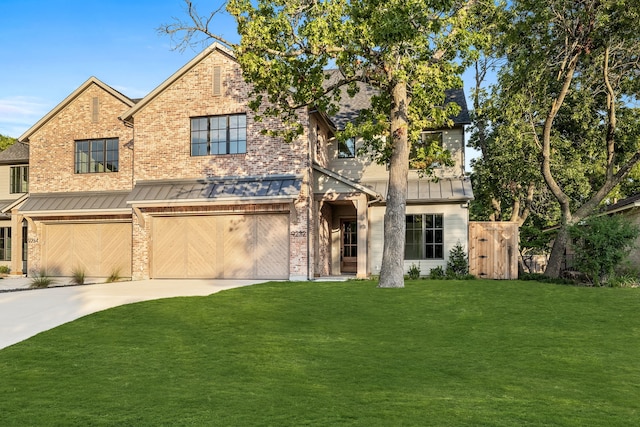 view of front of home with a front yard, a standing seam roof, brick siding, and driveway