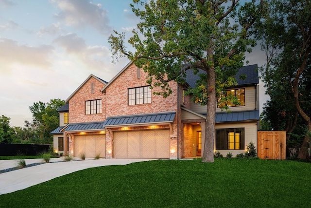 view of front of house with an attached garage, a standing seam roof, concrete driveway, and brick siding