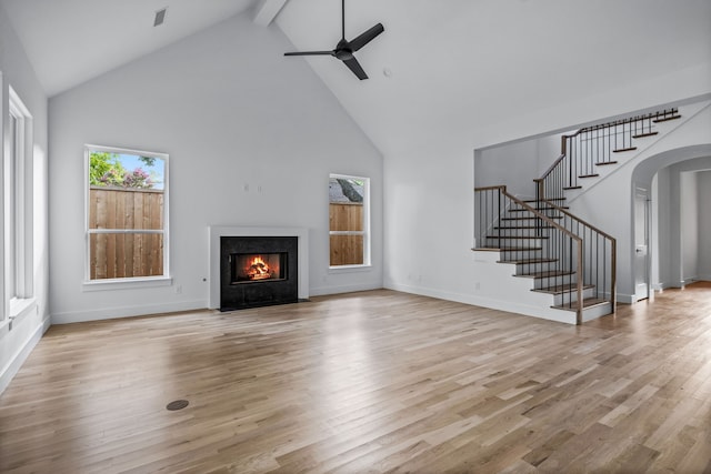 unfurnished living room featuring stairs, light wood-type flooring, arched walkways, and a high end fireplace