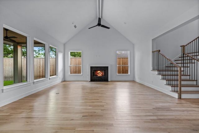 unfurnished living room with ceiling fan, a fireplace with flush hearth, and light wood-style flooring