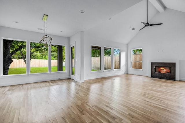 unfurnished living room featuring a fireplace with flush hearth, light wood-style floors, high vaulted ceiling, beamed ceiling, and baseboards