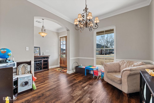 living area with baseboards, visible vents, arched walkways, wood finished floors, and crown molding