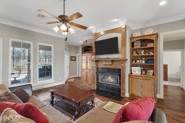 living room featuring dark wood finished floors, a fireplace, visible vents, ornamental molding, and baseboards