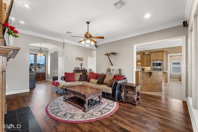 living area featuring a healthy amount of sunlight, visible vents, arched walkways, and dark wood-style flooring