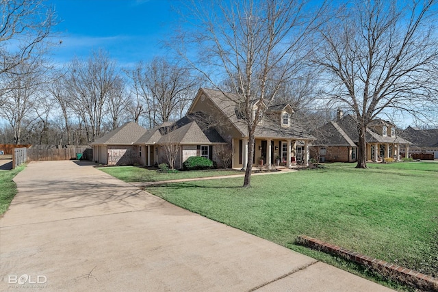 view of front facade featuring driveway, brick siding, a front yard, and fence