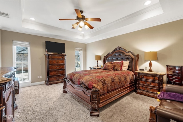 bedroom featuring ornamental molding, a tray ceiling, visible vents, and multiple windows