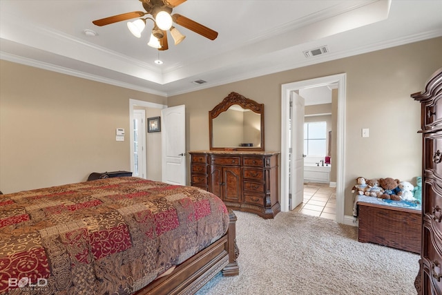 bedroom featuring light carpet, a tray ceiling, visible vents, and crown molding