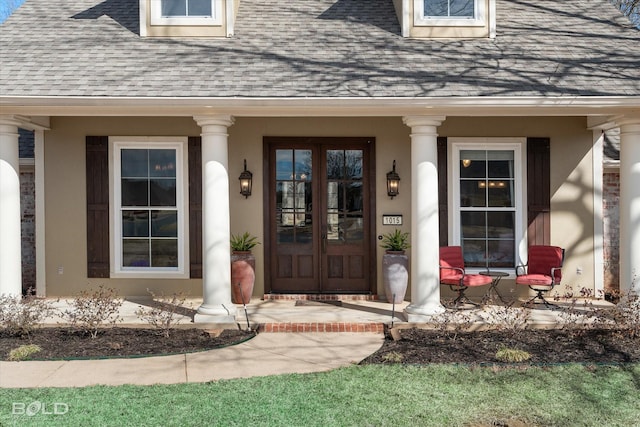 view of exterior entry with covered porch, roof with shingles, and stucco siding