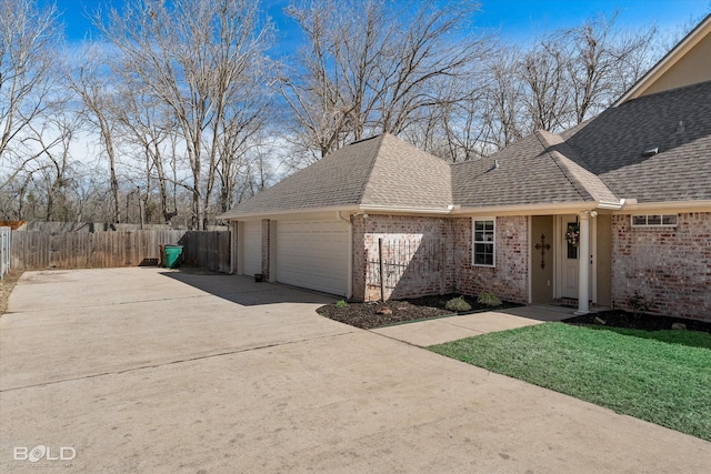 view of front of house with brick siding, fence, an attached garage, and roof with shingles