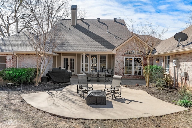 rear view of property featuring brick siding, a shingled roof, a patio area, and french doors