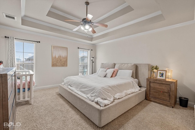 bedroom featuring a raised ceiling, multiple windows, and light carpet