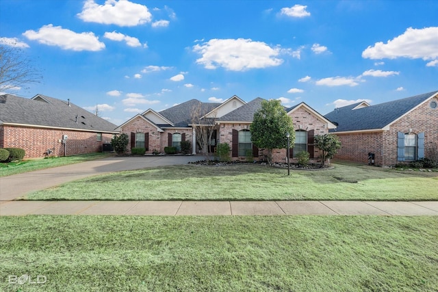 view of front facade featuring a shingled roof, brick siding, driveway, and a front lawn