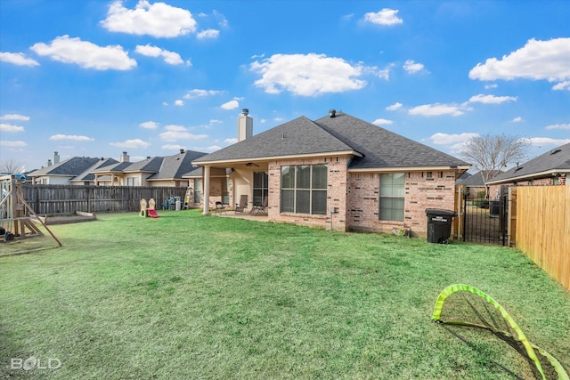 rear view of property featuring a patio, brick siding, a lawn, and a fenced backyard